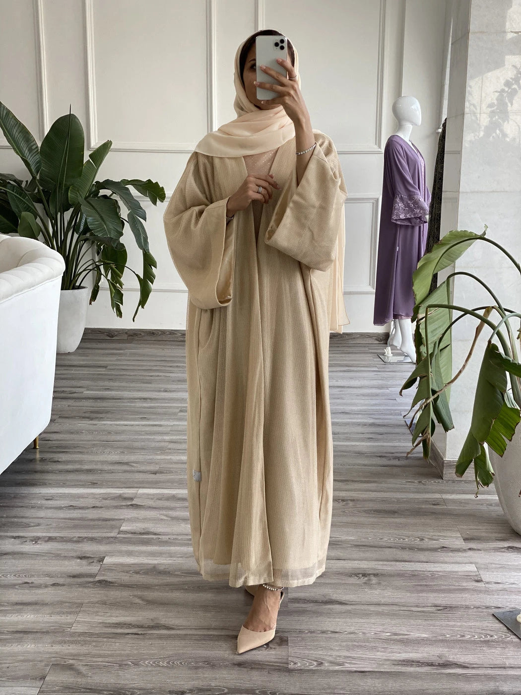 Elegant beige abaya with underdress, styled for a chic and modest look in a modern setting