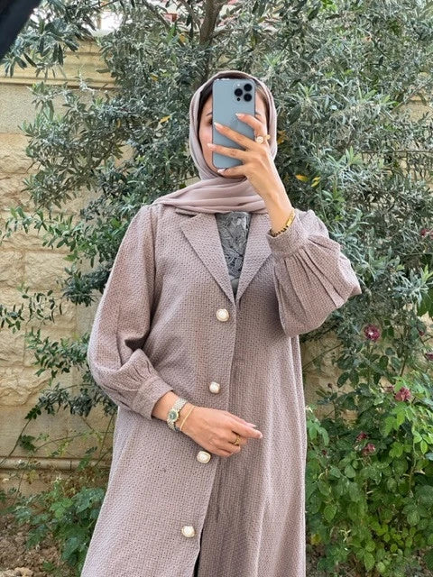 Stylish woman wearing a luxury abaya set Dubai with elegant buttons and soft fabric in a natural setting